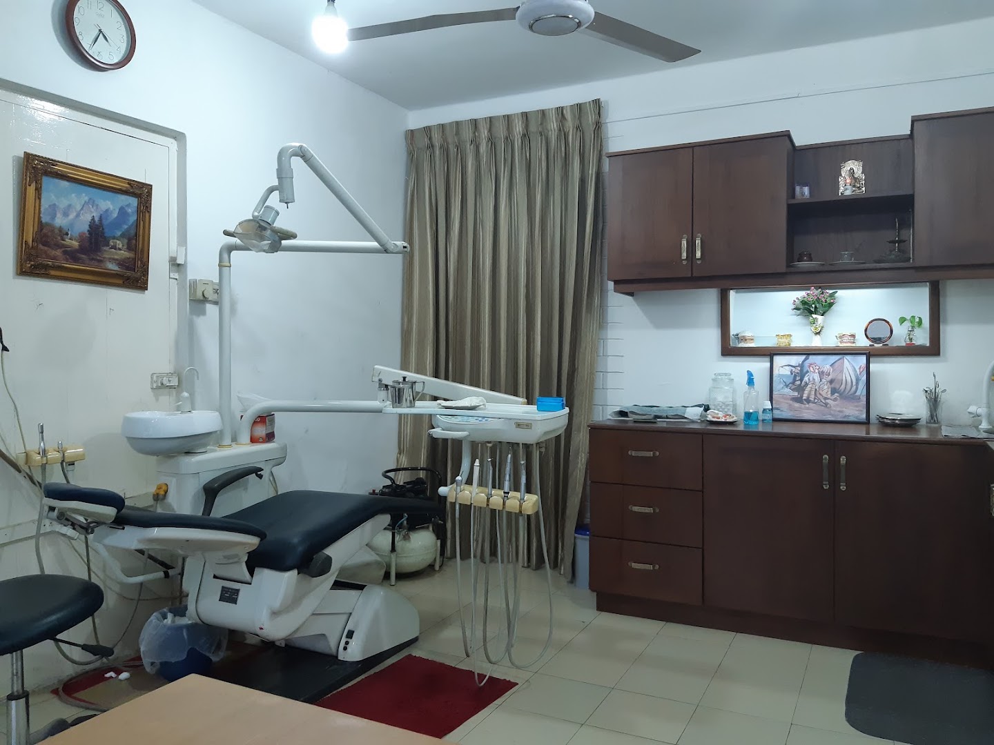 Dental chair, equipment, and walnut cabinetry in a clinic room